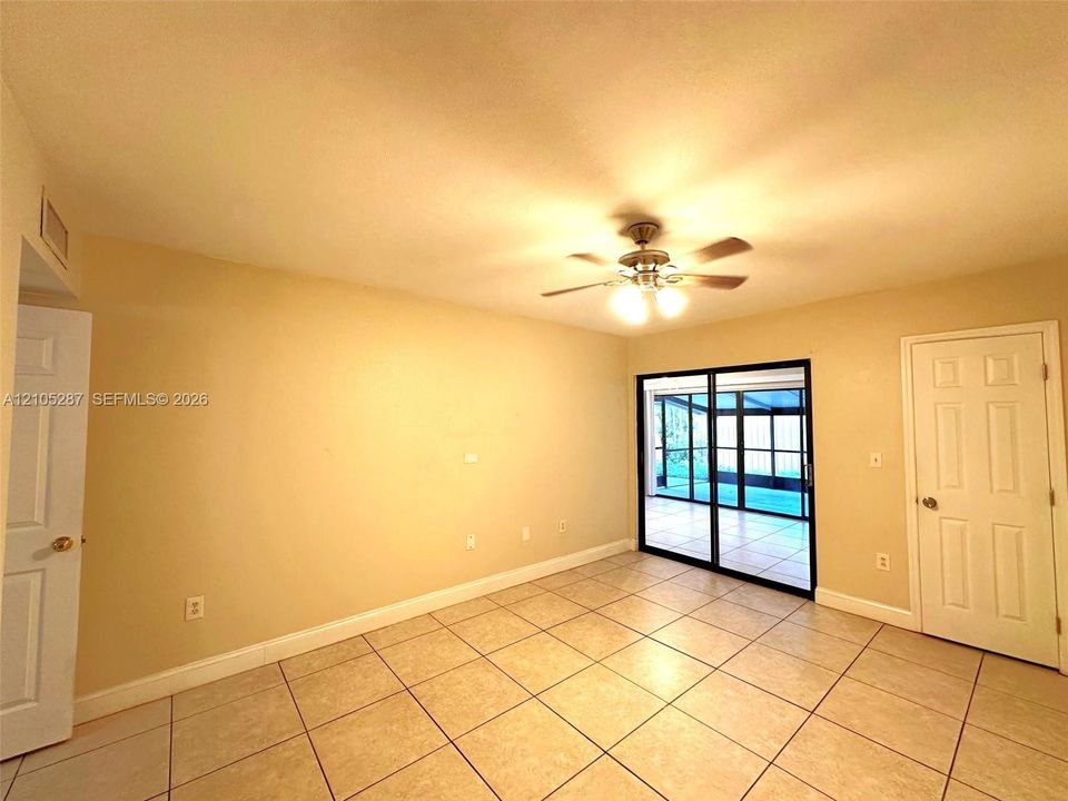 Recessed lighting with a ceiling fan, tiled flooring, and sliding glass doors leading to a screened enclosure