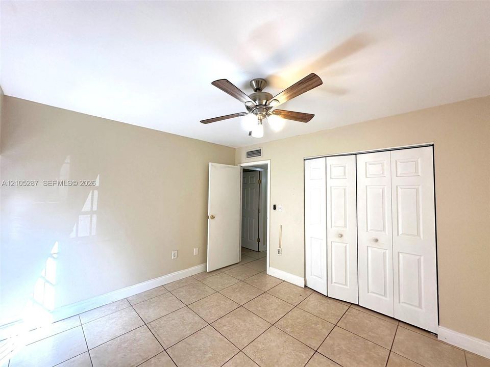 Neutral-toned walls, tile flooring, and a ceiling fan with integrated lighting