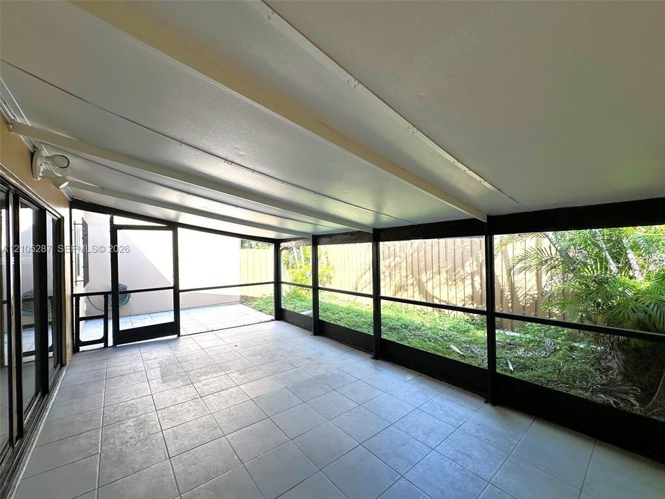 Expansive screened patio featuring a tiled floor, full coverage roof, and multiple sliding glass door access points