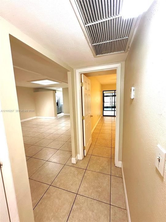 Tile flooring in a neutral tone, recessed lighting, and a white interior door