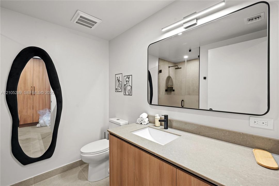 Floating vanity with wood-finish cabinetry, integrated rectangular sink, and matte black faucet