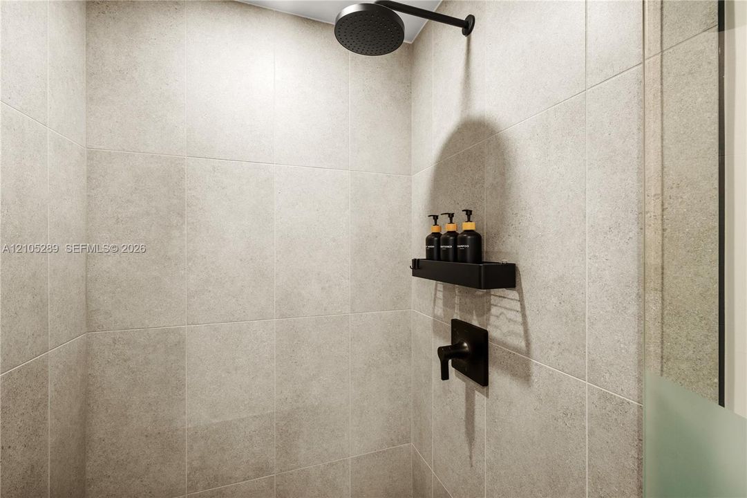 Tiled shower enclosure featuring a matte black rain shower head, integrated shower shelf, and coordinating matte black shower controls