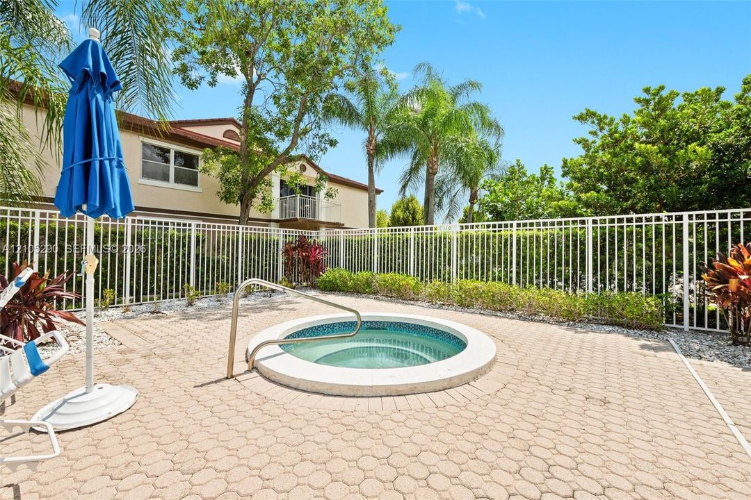 Circular spa with mosaic tile interior, surrounded by paver patio