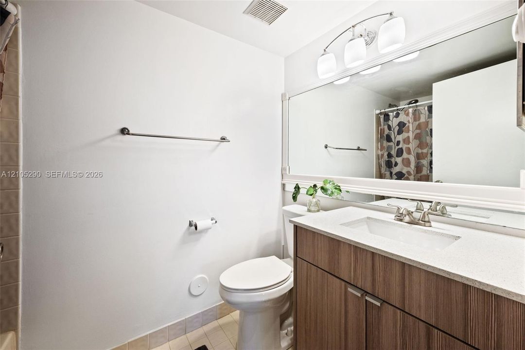Wood-finish vanity with a white countertop, undermount sink, and brushed nickel faucet
