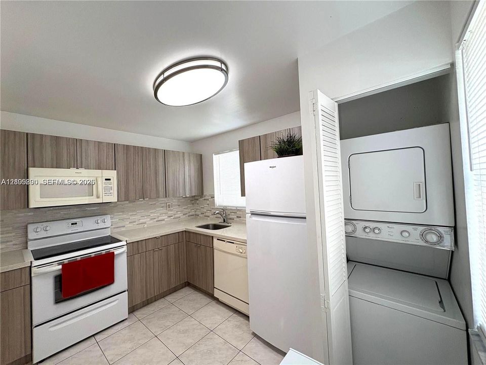 Kitchen featuring wood-finish cabinetry, tile flooring, and integrated white appliances