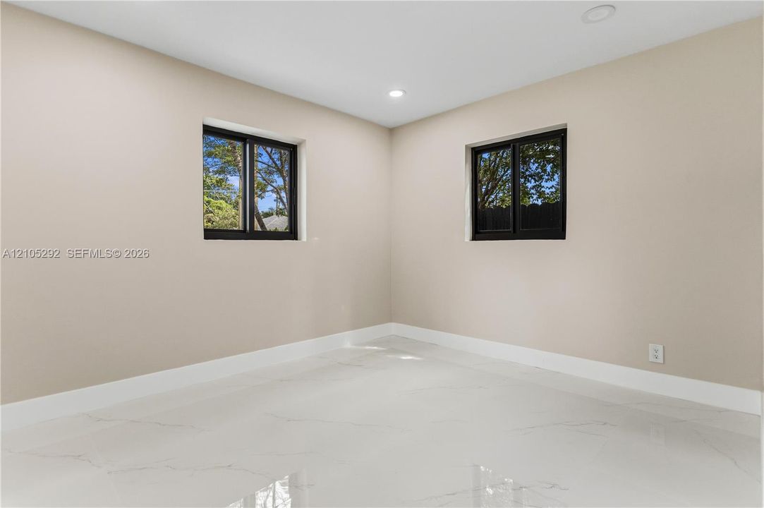 Smooth walls with a neutral finish, recessed lighting, white baseboards, and two windows with black frames
