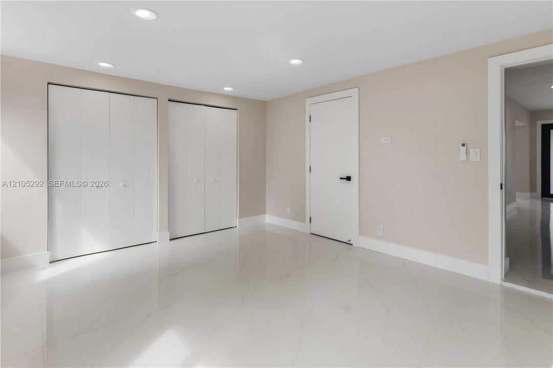 Recessed lighting, light-toned walls, and white tile flooring