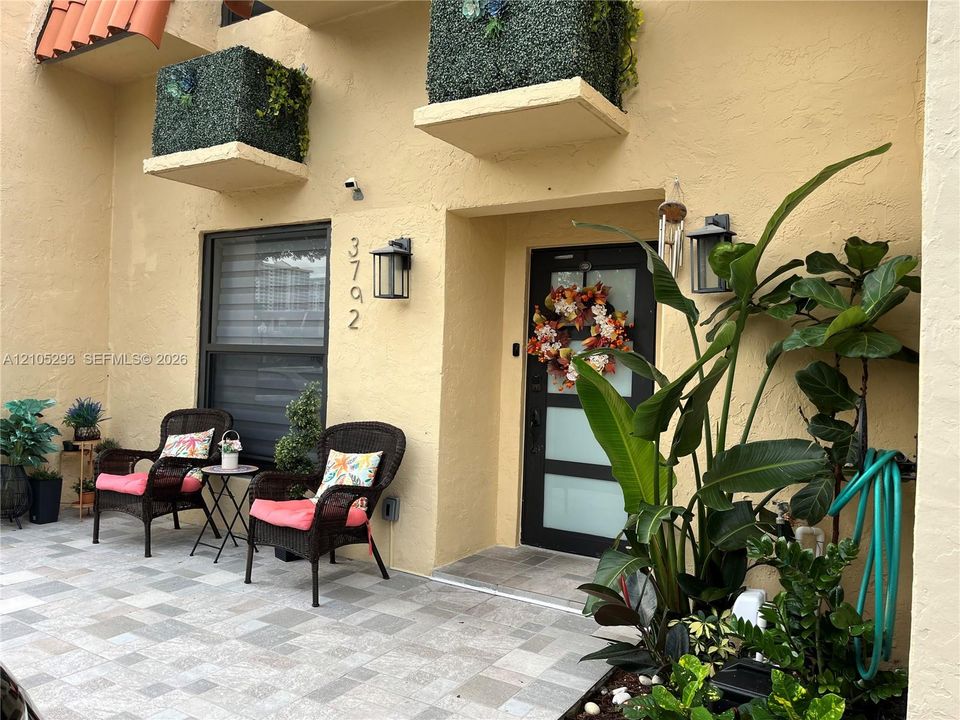 Exterior entrance featuring a tiled patio, stucco facade, integrated wall-mounted exterior lighting, and a modern entry door with frosted glass panels
