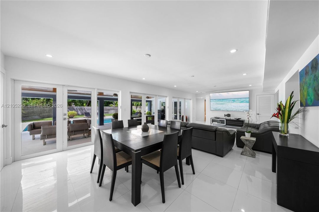 Open-concept living space featuring high-gloss tile flooring, recessed lighting, and multiple sets of glass paneled doors providing access to the rear exterior