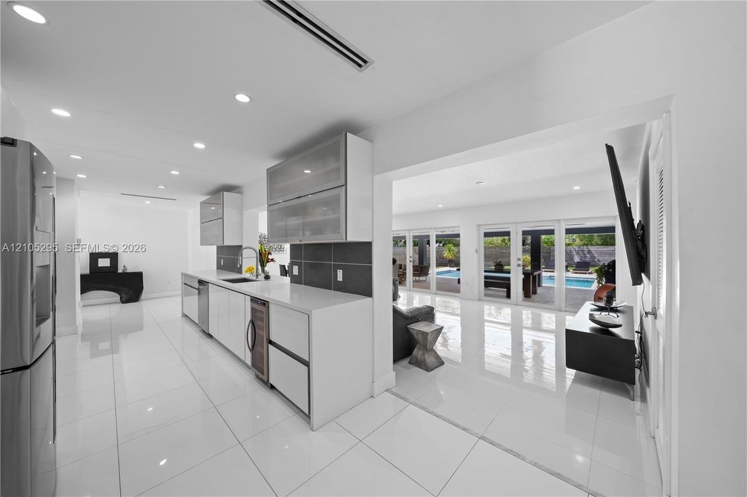 Kitchen featuring white flat-panel cabinetry, quartz countertops, dark tile backsplash, recessed lighting, and large-format tile flooring