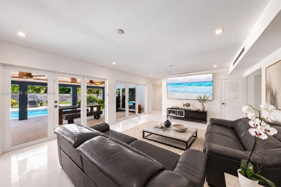 Open-concept living space featuring high-gloss tile flooring, recessed lighting, and multiple sets of glass impact doors