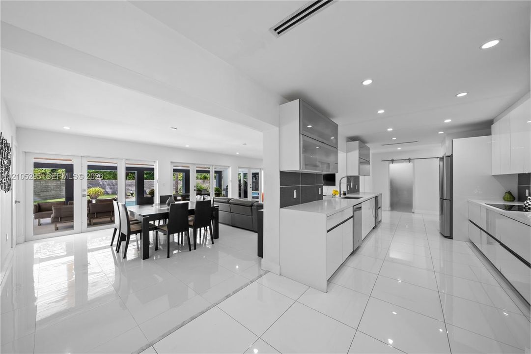 Kitchen featuring white gloss cabinetry, quartz countertops, tile flooring, recessed lighting, and a stainless steel appliance suite