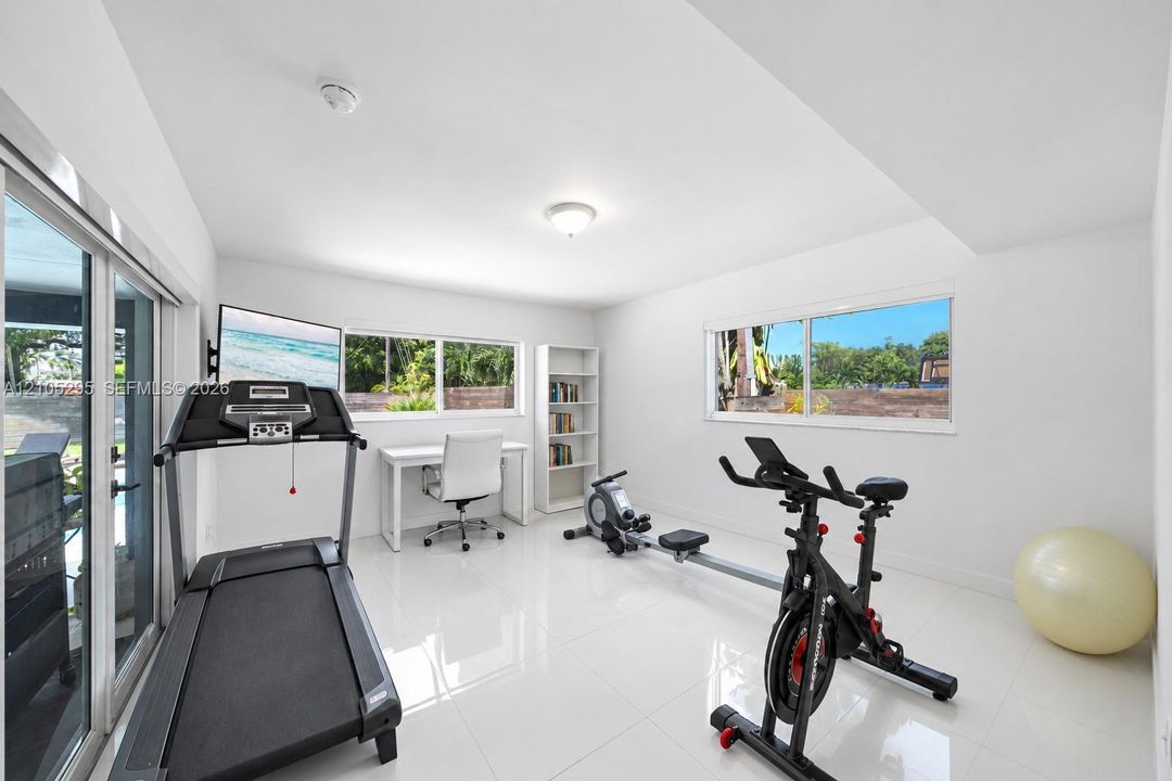 Bright, neutral room featuring polished tile flooring, sliding glass doors, and multiple windows providing natural light