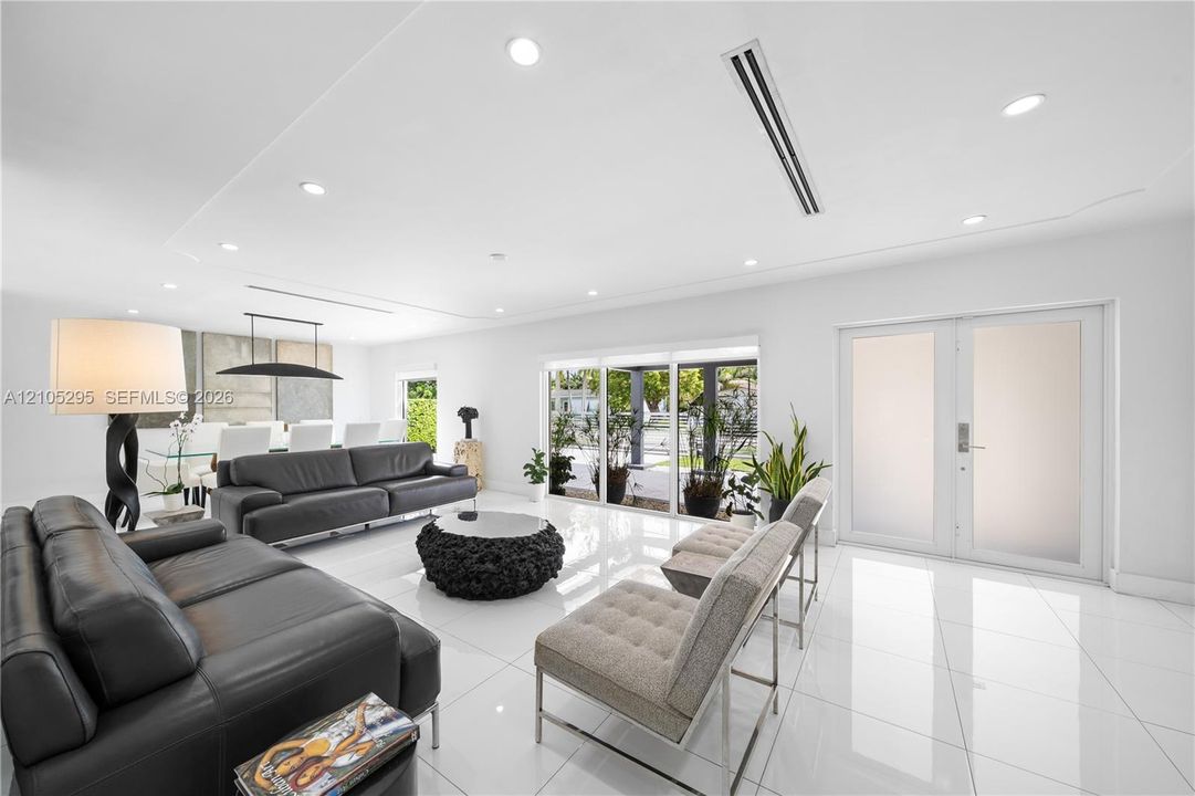 Open-concept living space featuring high-gloss tile flooring, recessed lighting, linear HVAC diffusers, and sliding glass doors
