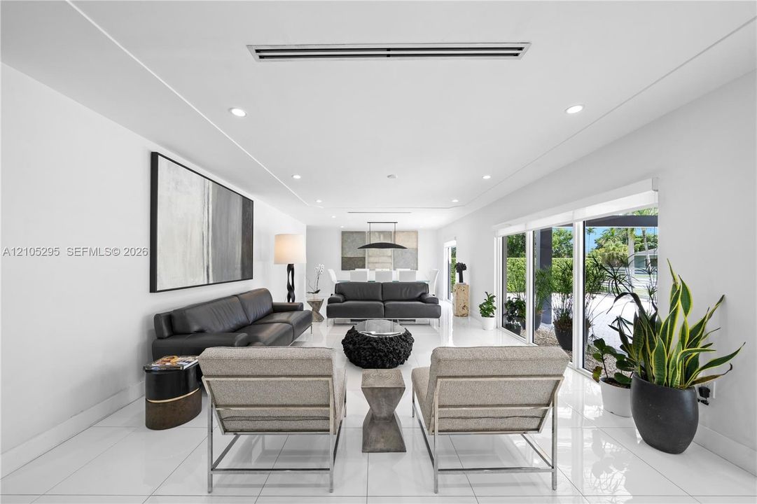 Open-concept interior featuring large-format tile flooring, recessed ceiling lighting, linear ceiling-integrated climate control, and extensive floor-to-ceiling impact glass doors