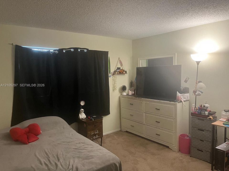 Textured ceiling, wall-to-wall carpeting, and a window with dark curtains