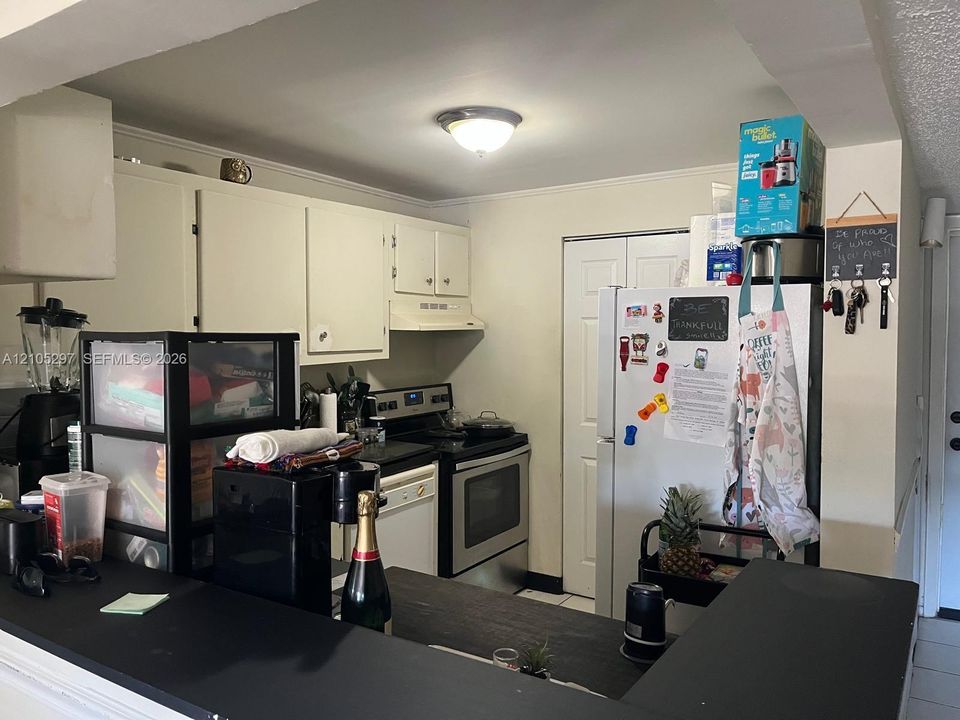 Kitchen featuring white cabinetry, stainless steel appliances, and a black countertop peninsula