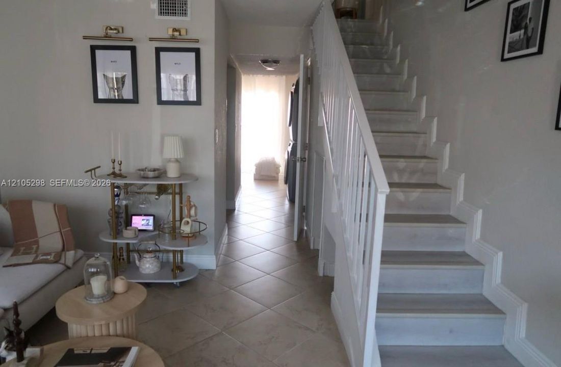 Neutral paint colors, tile flooring, white staircase, white wall paneling, recessed lighting