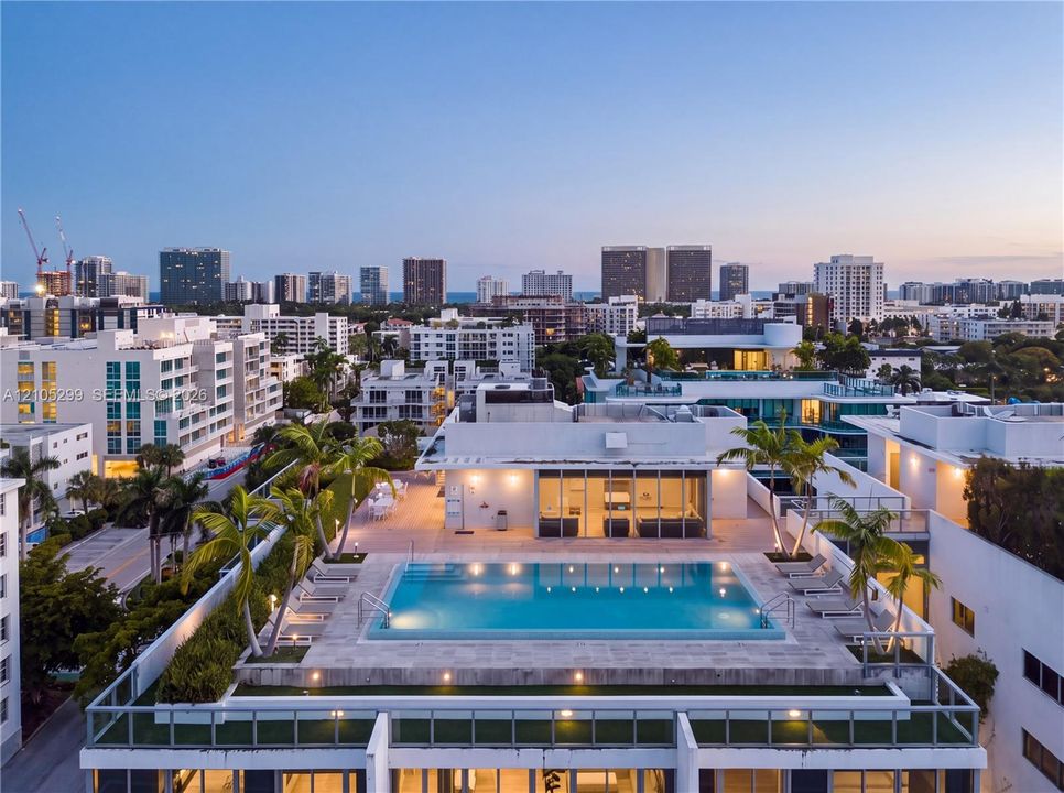 Rooftop pool with integrated lighting, surrounding paved patio, and perimeter landscaping