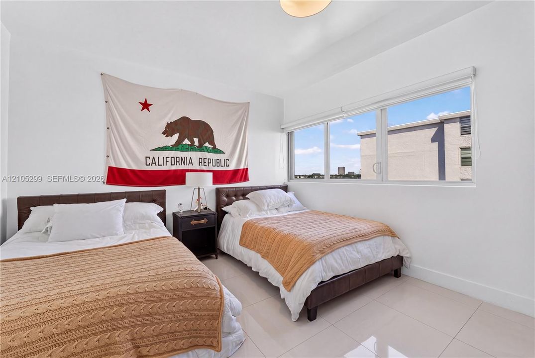 Recessed lighting, large window with roller shades, white walls, and tile flooring