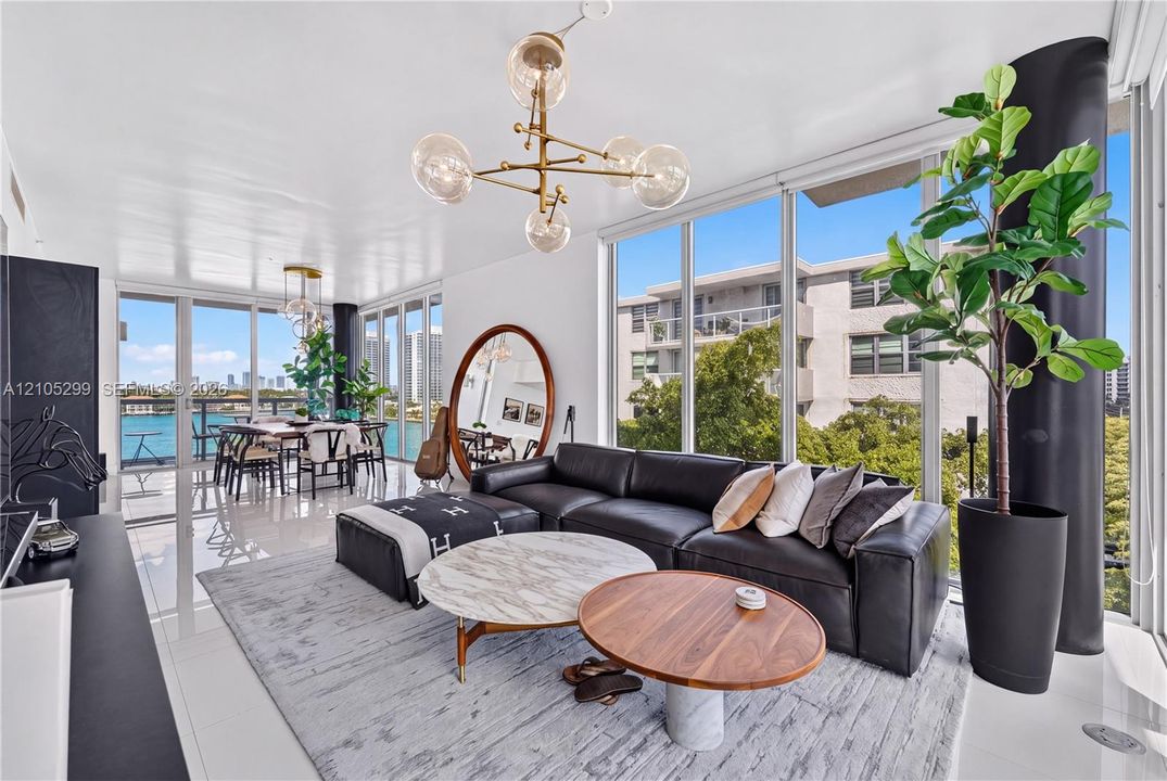 Expansive window walls, glossy tile flooring, recessed lighting, and a modern chandelier