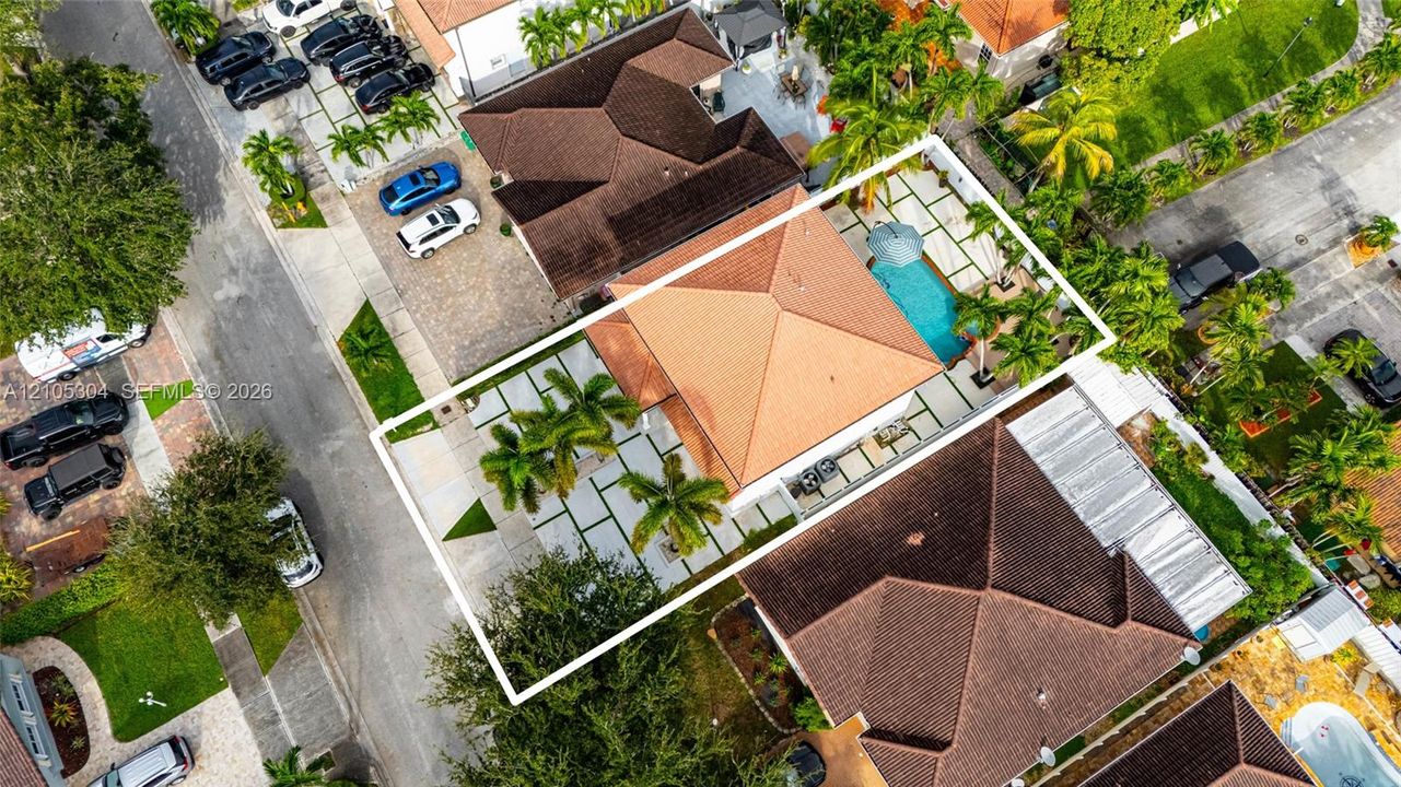 Aerial view of property featuring a hip roof, swimming pool, paver patio, and mature landscaping