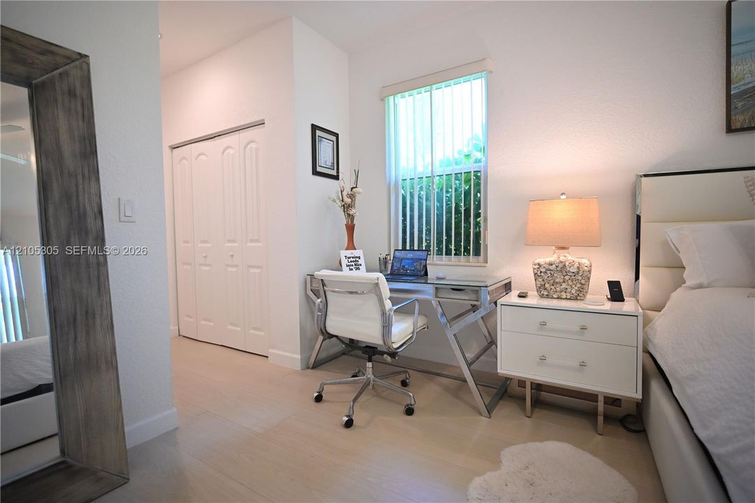 Wood-finish flooring throughout, featuring a window with vertical blinds, and a built-in closet with bifold doors