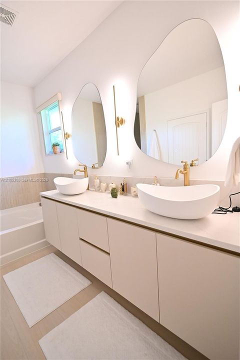 Floating vanity with dual vessel sinks, wall-mounted fixtures, and integrated lighting