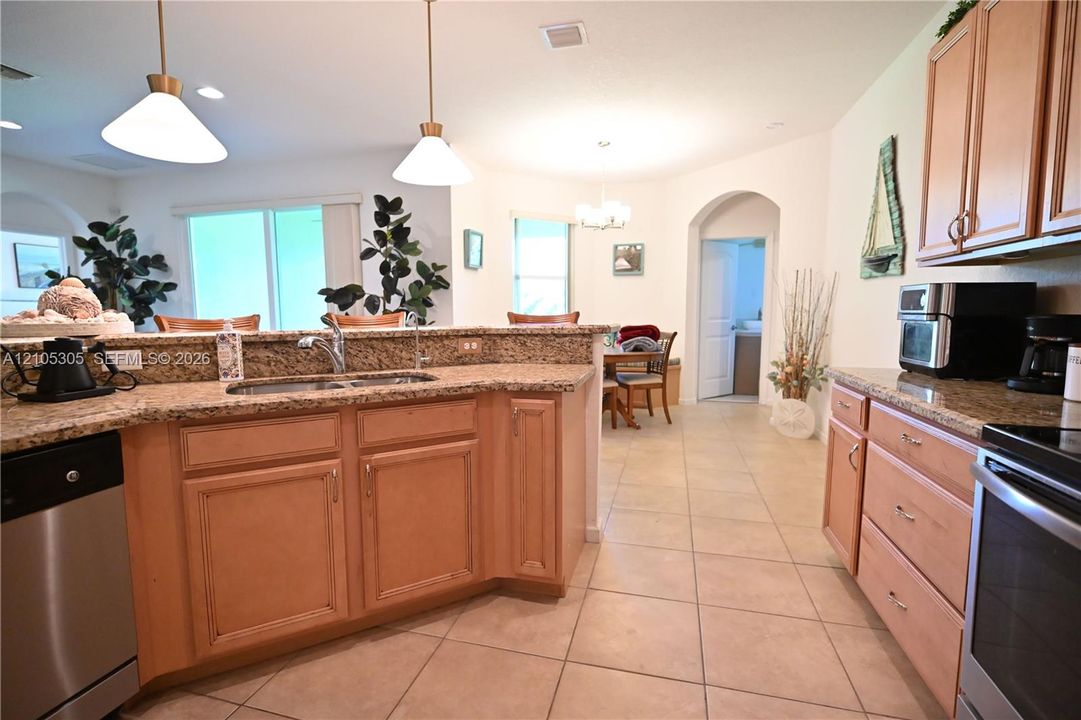 Kitchen featuring light wood-finish cabinetry, stainless steel appliances, and a double basin sink