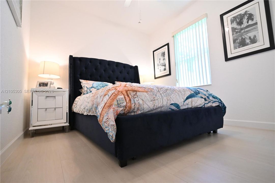 Wood-finish flooring, white walls, and a window with vertical blinds