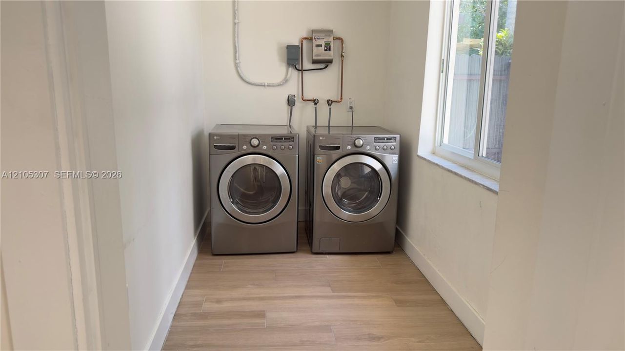 Dedicated laundry space featuring wood-finish flooring and a single-hung window