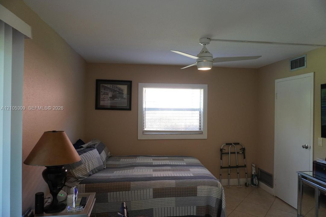 Room featuring a central window, white ceiling fan with integrated lighting, neutral wall paint, and tile flooring