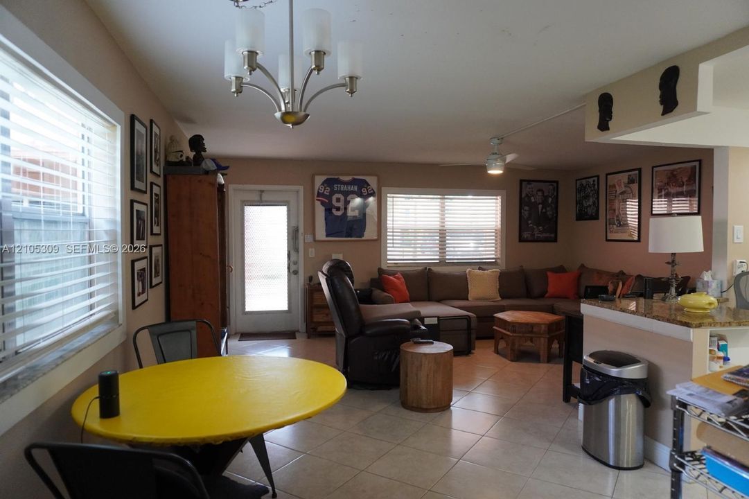 Tile flooring, multi-light chandelier, ceiling fan, and stone-surfaced kitchen peninsula