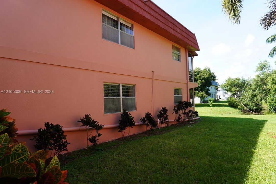 Two-story exterior featuring smooth stucco siding, a mansard roofline, multi-pane windows, and manicured perimeter landscaping