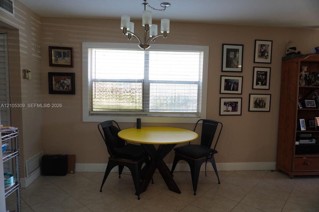 Interior area featuring large window with wide casing, tile flooring, and five-arm chandelier light fixture