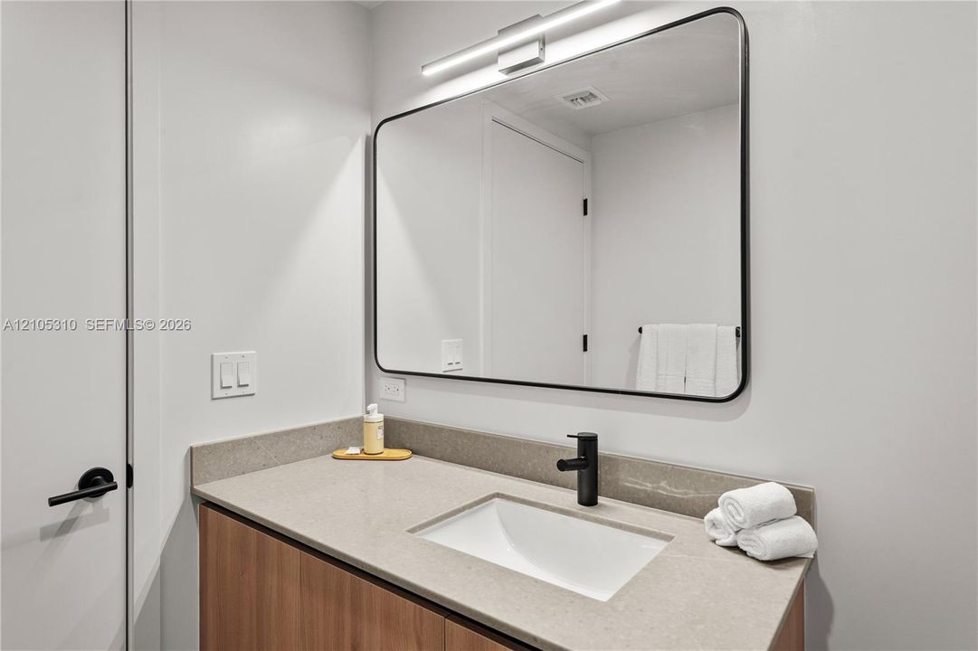 Integrated vanity with wood-finish cabinetry, under-mount sink, and dark faucet