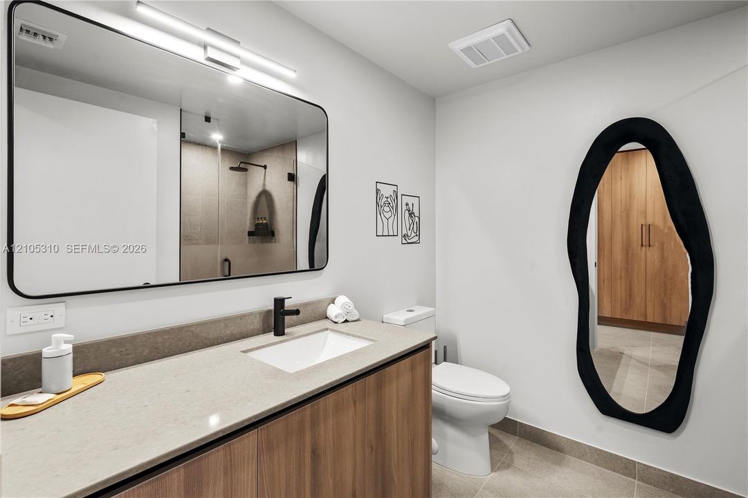 Floating vanity with wood-finish cabinetry, light-toned countertop, and undermount sink