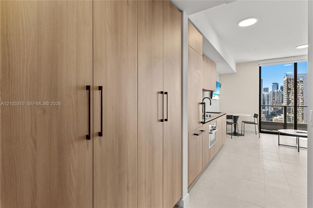 Integrated kitchen with wood-finish cabinetry, stainless steel appliances, and a matte black faucet