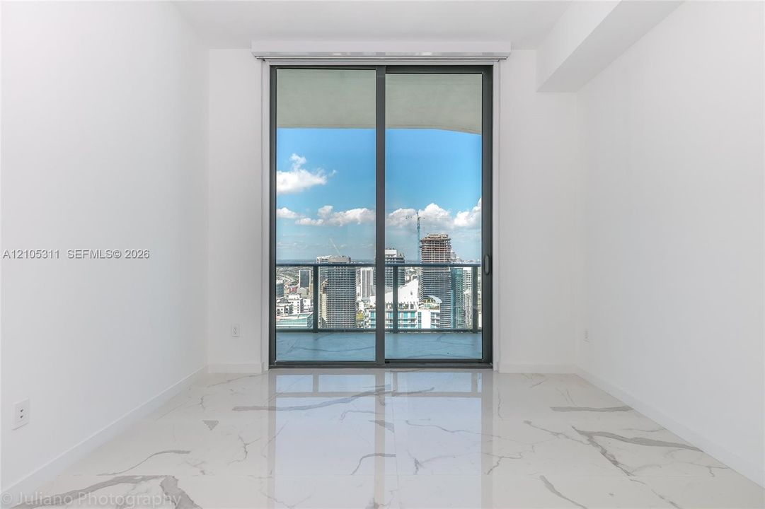 Expansive sliding glass doors, cityscape, balcony, white walls, and marble-finish flooring