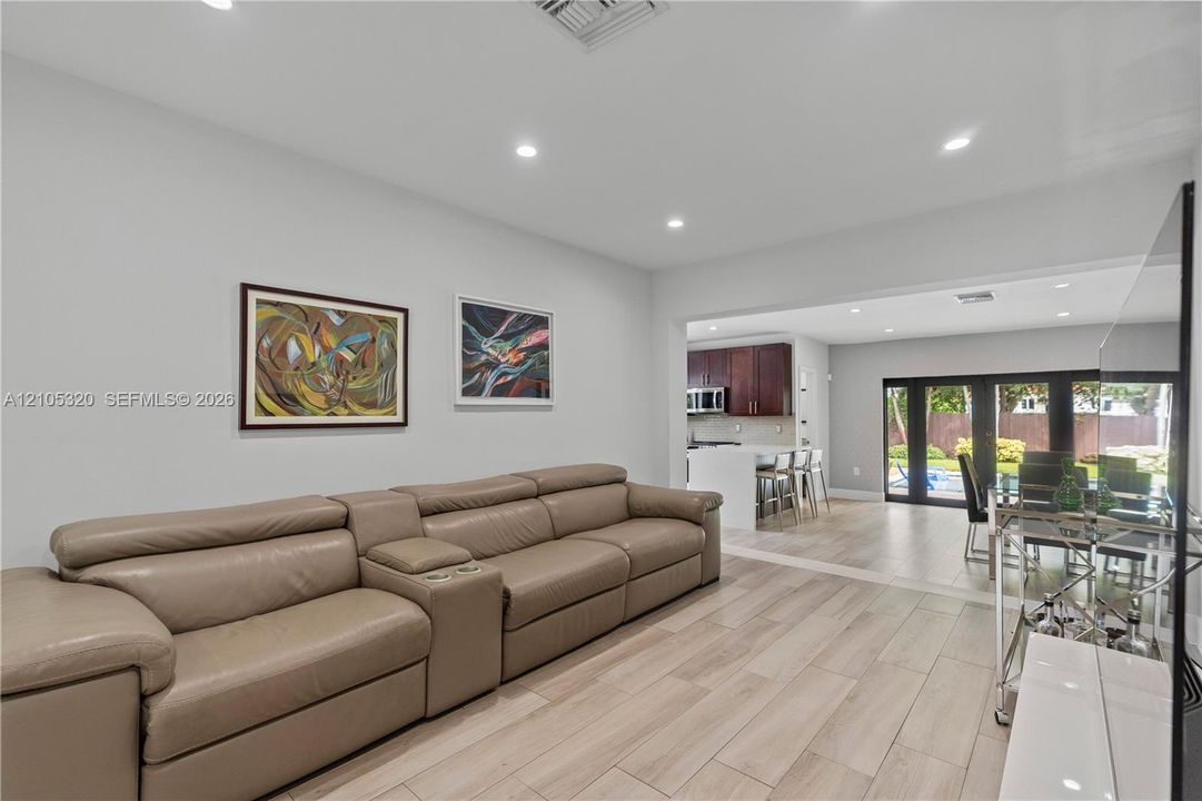 Recessed lighting, wood-finish flooring, cased opening to kitchen, kitchen with white island, dining area with glass doors to exterior