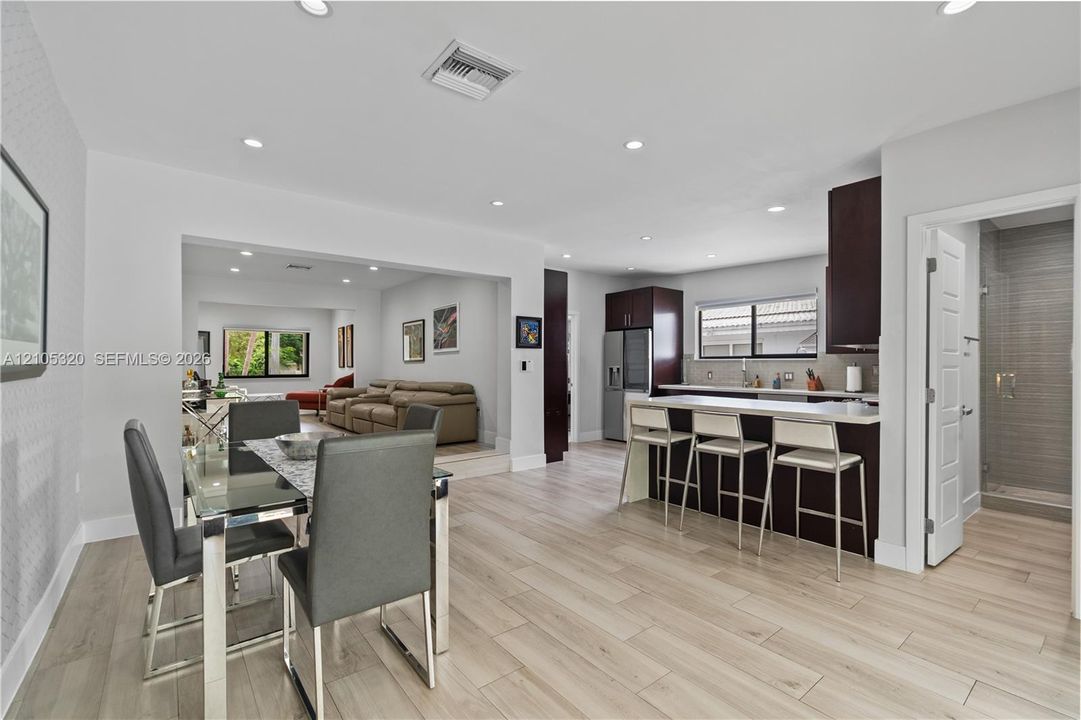 Light wood-finish flooring, recessed lighting, and a kitchen island with seating