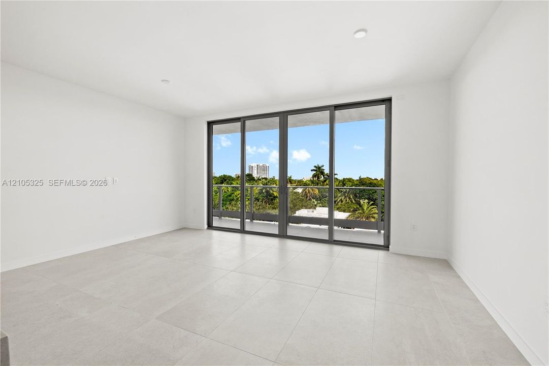 Floor-to-ceiling sliding glass doors, balcony with glass railing, recessed lighting, and large format tile flooring