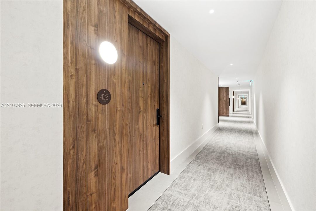 Wood-finish entry door with modern sconce lighting and black hardware