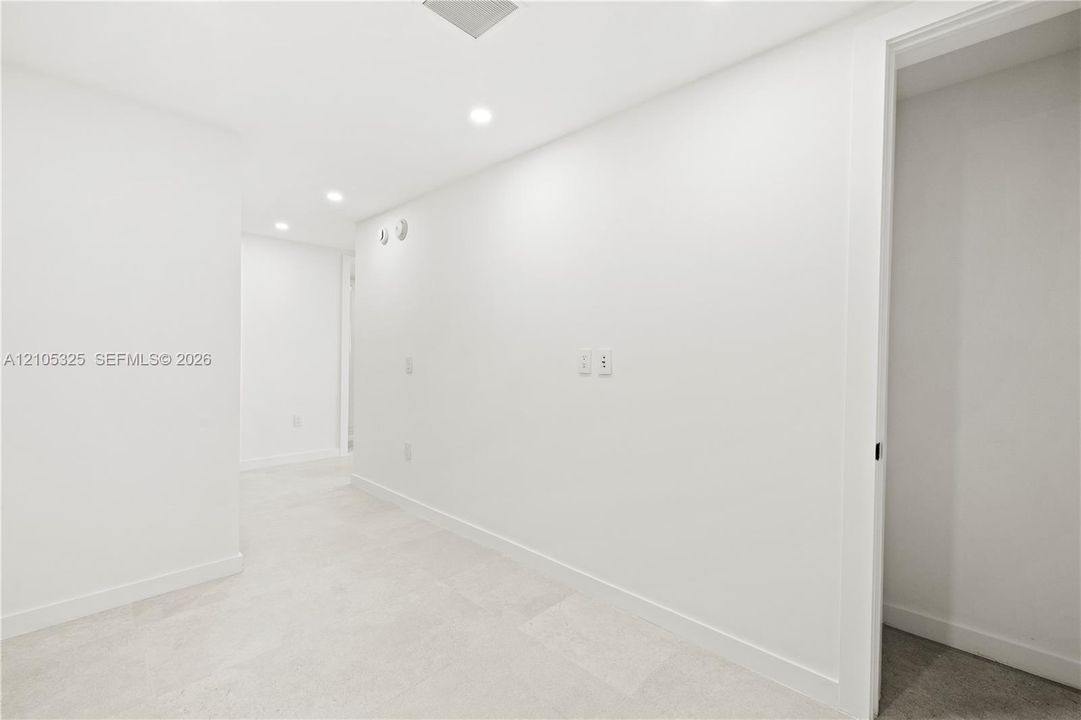 Recessed lighting, light-toned carpeting, white wall finishes, crisp white trim, and a doorway