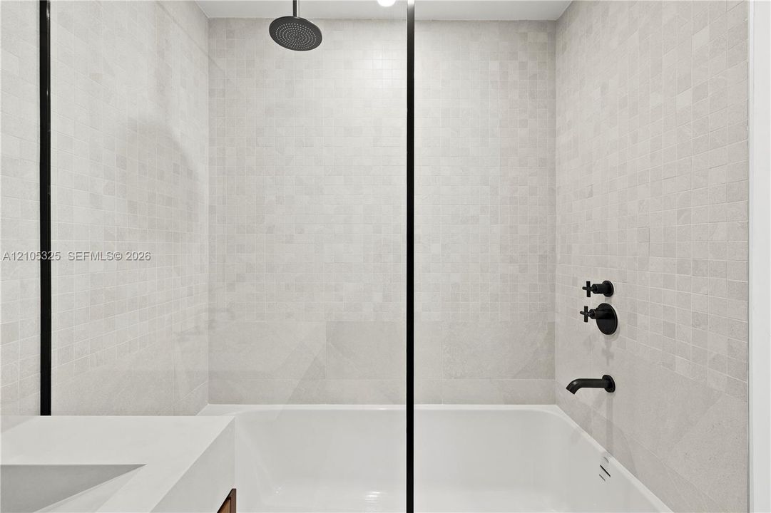 Shower-over-tub combination with black matte fixtures and a rainfall showerhead