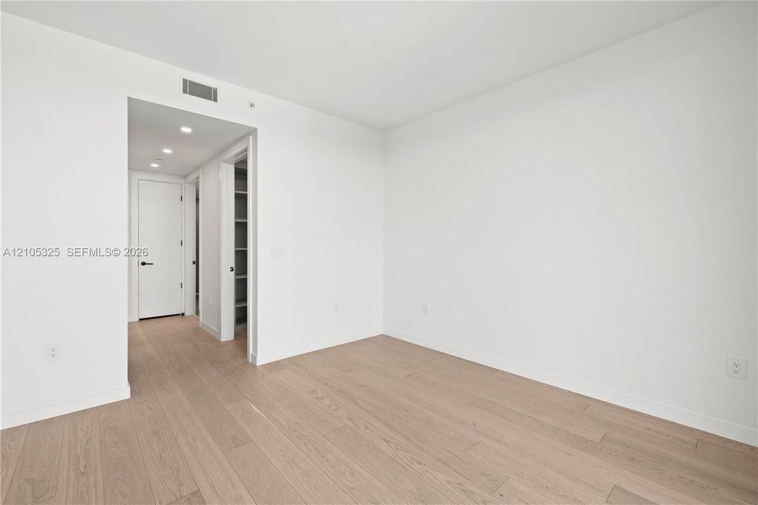 Recessed lighting, wood-finish flooring, white walls, built-in shelving, and flush-panel doors