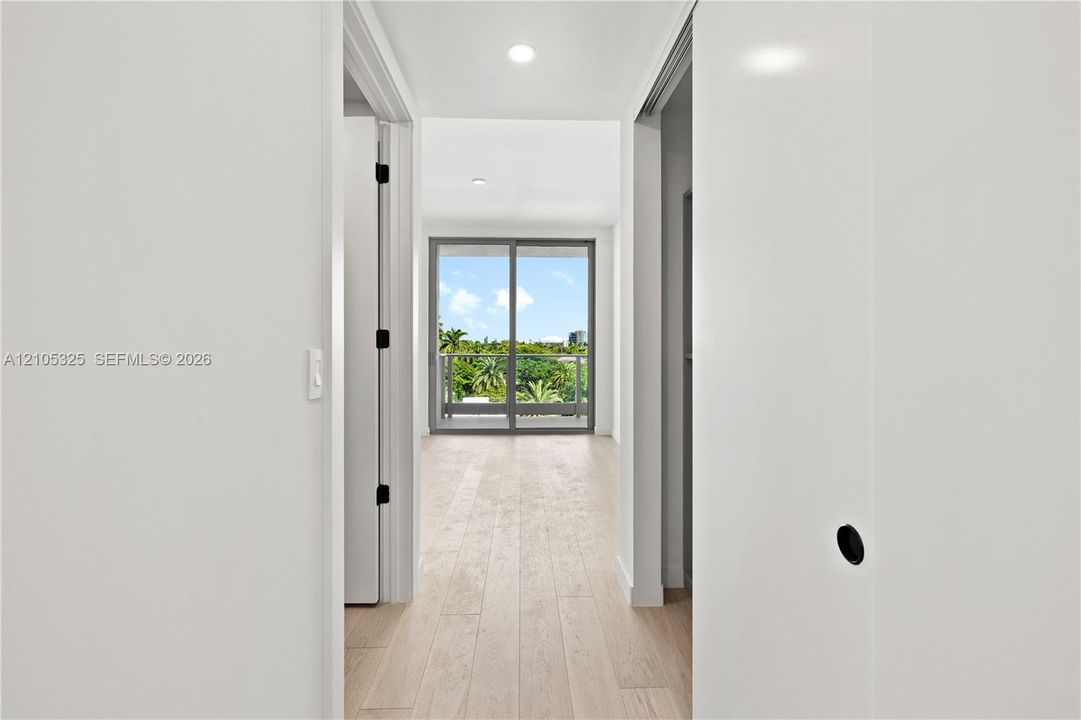Light wood-finish flooring extending into the distance, with crisp white walls and recessed lighting
