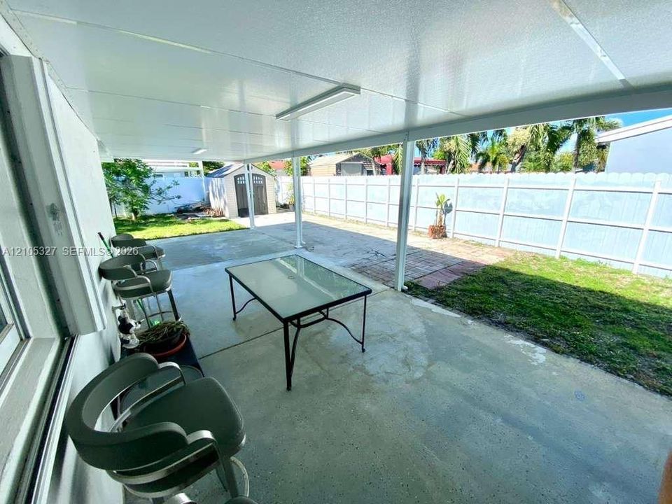 Covered patio with concrete flooring, fenced backyard, and a storage shed