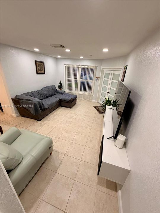 Recessed lighting, tile flooring, window with vertical blinds, and a double-door entry with frosted glass panels