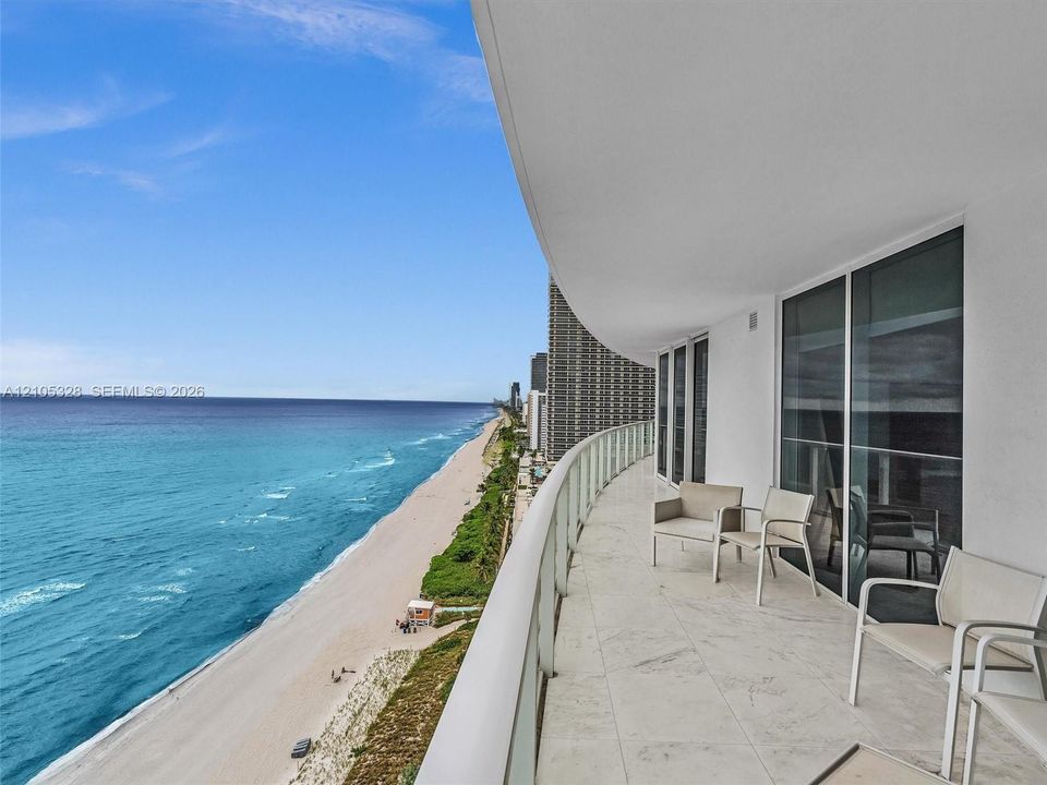Expansive private balcony featuring glass railings and breathtaking, unobstructed panoramic ocean views.